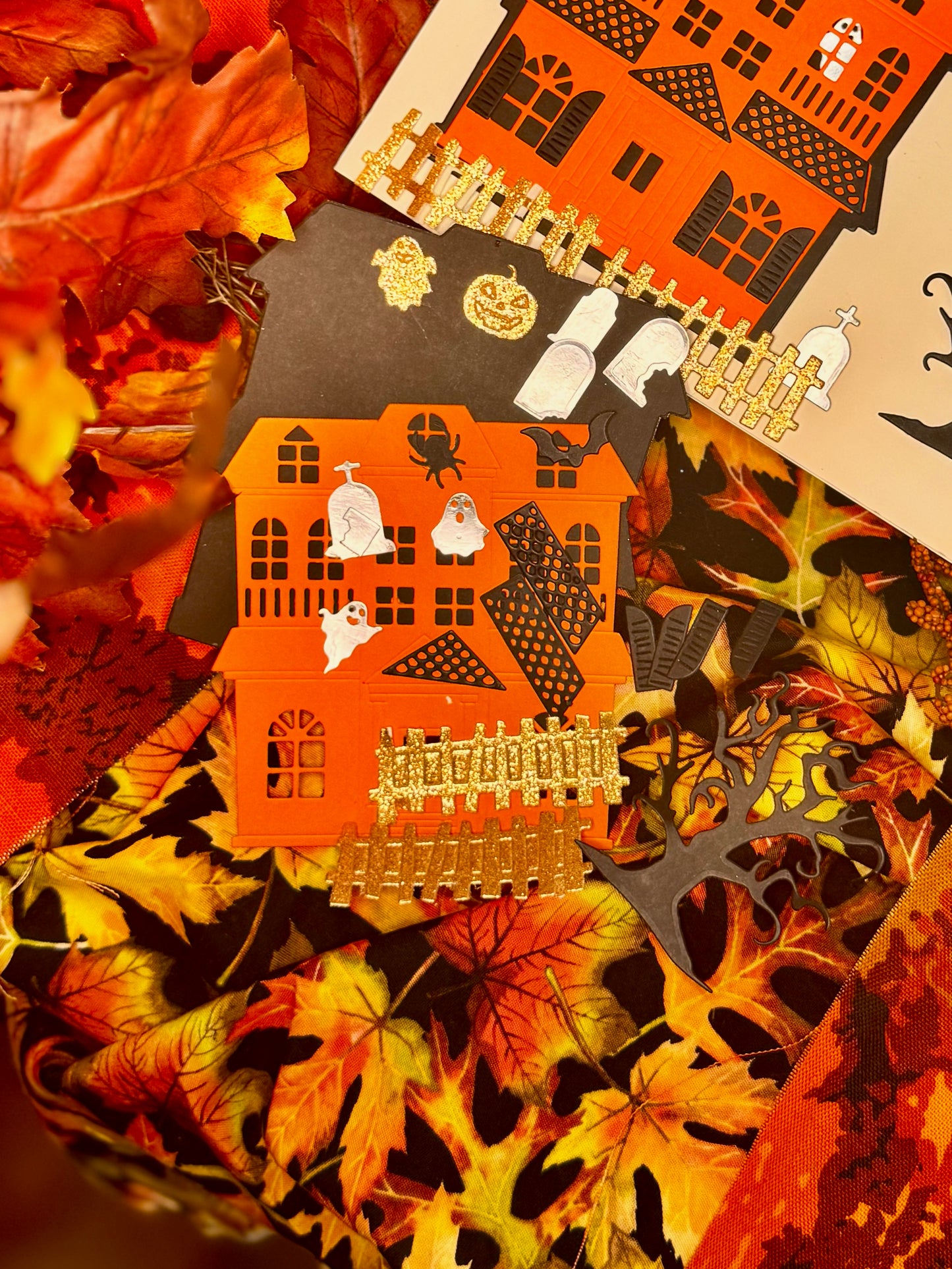 close up paper cut-out haunted houses decorated with small Halloween stickers, such as ghosts, a spider, a bat, tombstones, a jack-o-lantern.