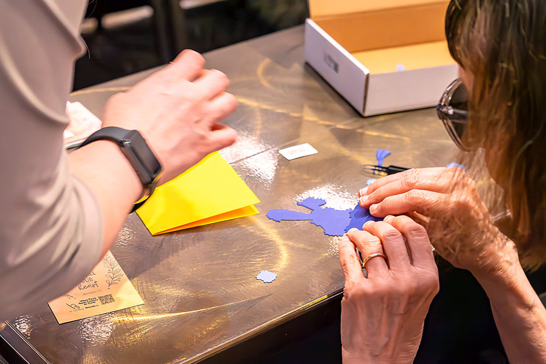 Two individuals working on a card together. Participant is feeling the whole bunny to understand placement of pieces.