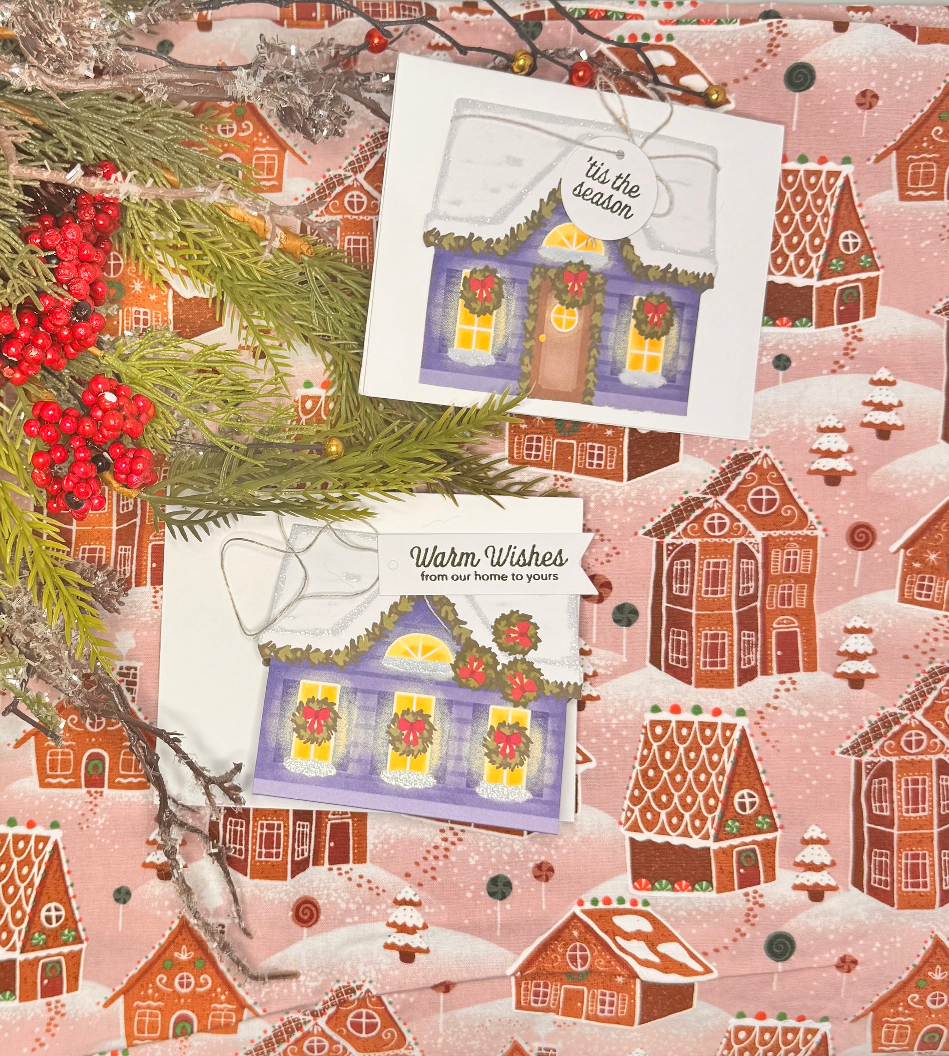 A House Full of Cheer
Our final design carries the warmth of the holidays without leaning into any one tradition. A soft, snowy village house with gentle garlands and wreaths says “you’re on my mind” in the coziest way. It’s perfect for neighbors, friends, or faraway family  and refreshingly Christmas-neutral.  Christmas-themed cards with houses and holly on a matching patterned background