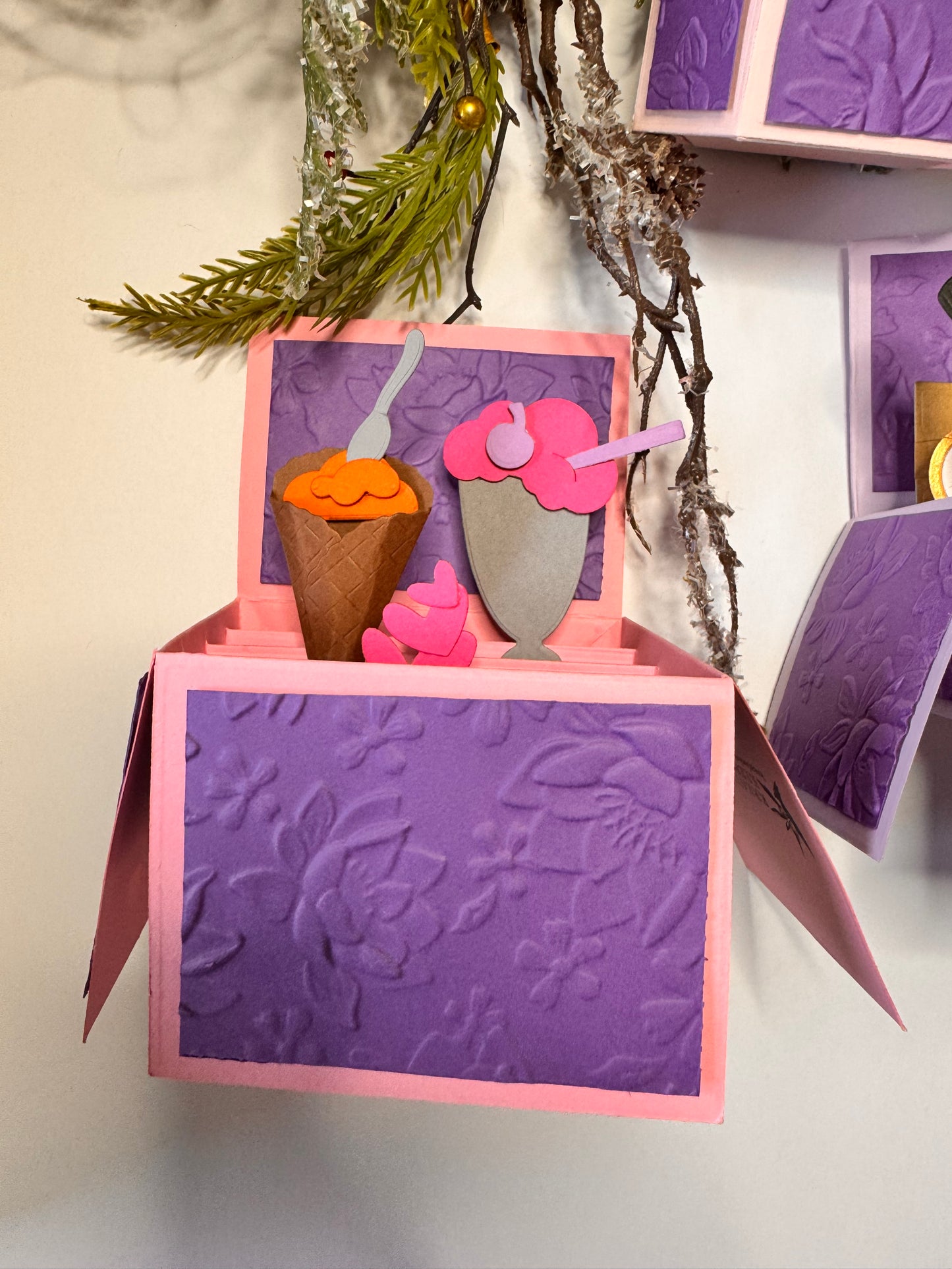 an ice cream cone with sherbet orange , 3 pink hearts, and a grey milkshake glass with pink ice cream, a purple cherry and straw. 